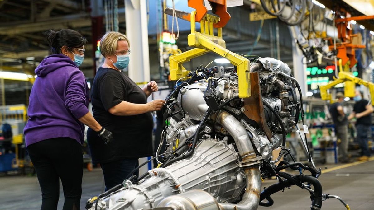 Autoworkers assembling a powertrain.