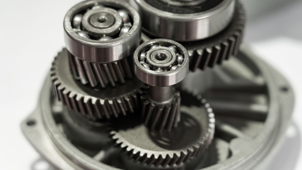 A shiny dark gray electric motor internal gear mechanism on a white surface.