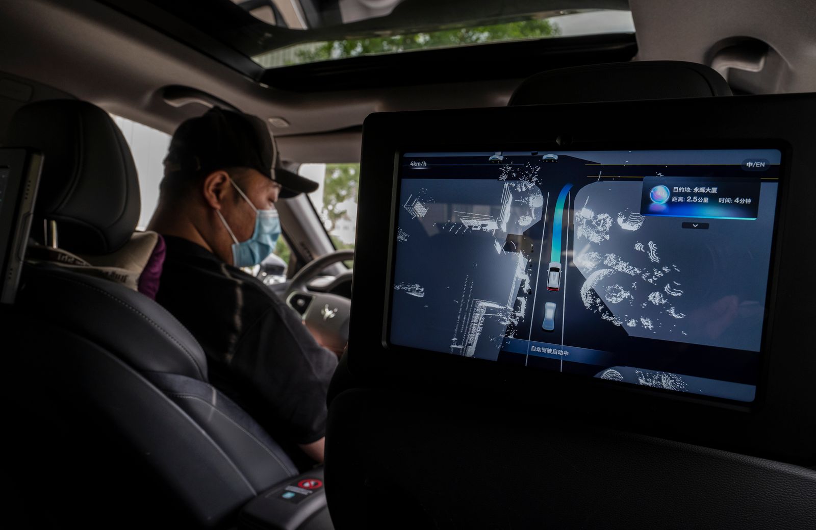 A monitor shows the real-time location of the vehicle as a "safety driver" sits in an Apollo Moon robotaxi.