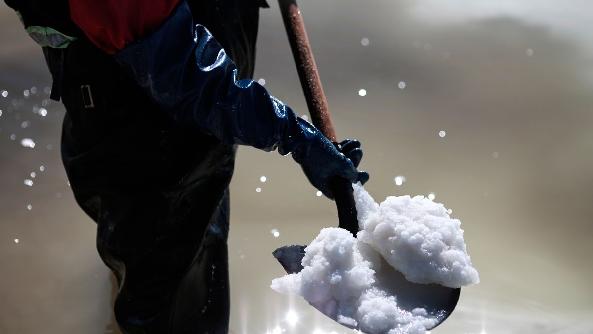 A worker uses a shovel to move the raw material for the manufacture of lithium carbonate at the Llipi pilot Planton August 14, 2022 in Uyuni, Bolivia.